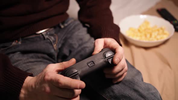 A Man Plays a Game Console with a Joystick