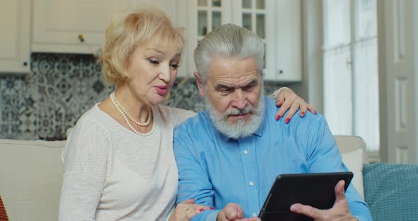 Senior Old Couple Talking Using Digital Tablet Computer Modern Tech at Home alt