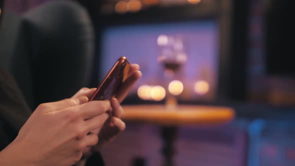 Women look the phone and drinking wine in her house. Close-up