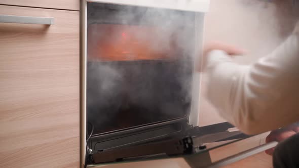 Man Opens an Oven Full Smoke in Kitchen alt
