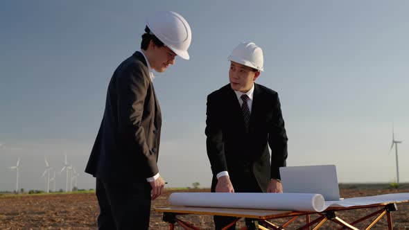 In the wind turbine field, businessman and engineer are consulting and brainstorming