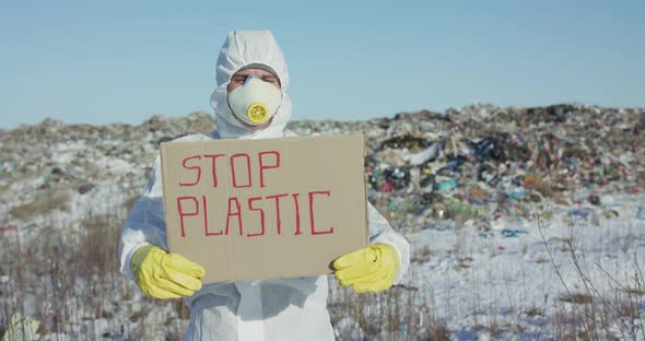 Man Wore in Protective Suit Show Protest Sign "Stop Plastic" at Plastic Landfill alt