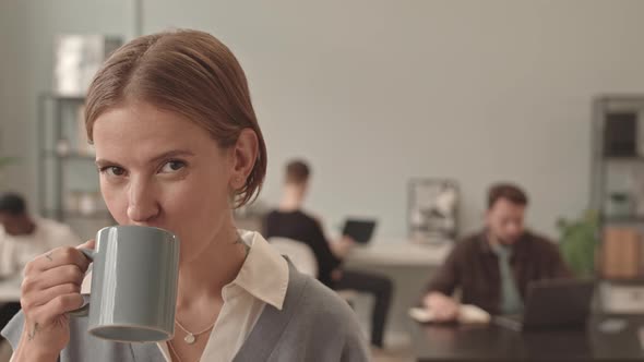 Woman Drinking Coffee Posing in Office alt