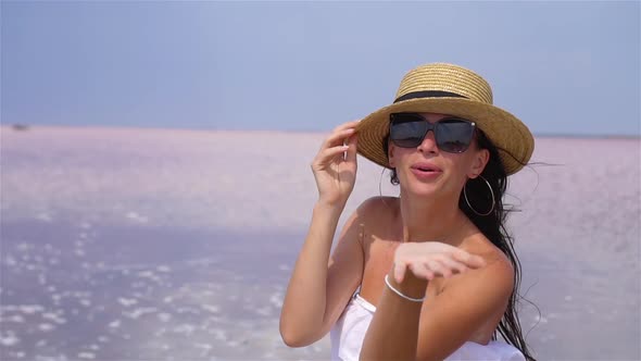 Woman in Hat Walk on a Pink Salt Lake on a Sunny Summer Day.