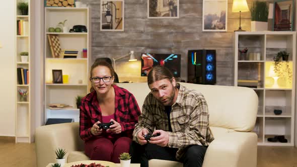 Young Couple Jumping Up From the Couch Celebrating Their Victory alt