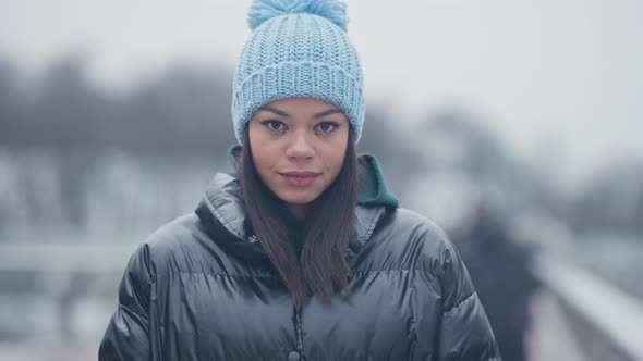 Young Confident Woman with Smeared Mascara Looking at Camera and Smiling on Misty Winter Day alt