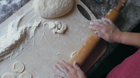 Closeup Hands of Senior Female is Rolling a Dough for Dumplings at Home Kitchen