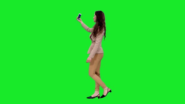 Slender Girl Having a Video Chat via Smartphone while Walking on Green Screen