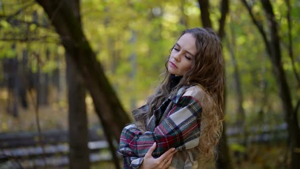 Portrait of a Woman with Curly Hair and a Plaid Coat in an Autumn Park alt