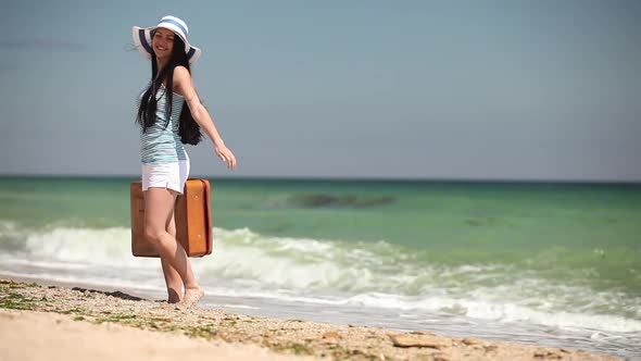 Young woman with travel suitcase on the beach
