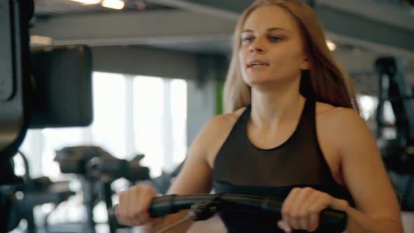 Woman Training Her Hands in Gym Using Professional Workout Machi alt