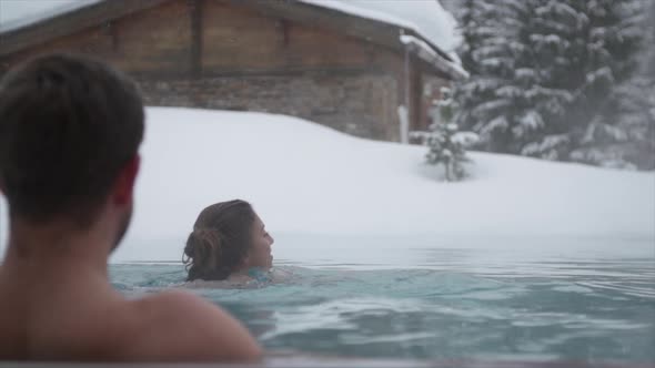 A man and woman couple playing in an outdoor a pool at a luxury spa resort alt