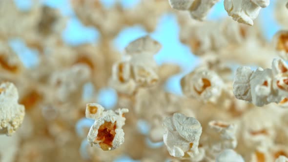 Super Slow Motion Shot of Popcorn on Blue Background After Being Exploded at 1000Fps alt