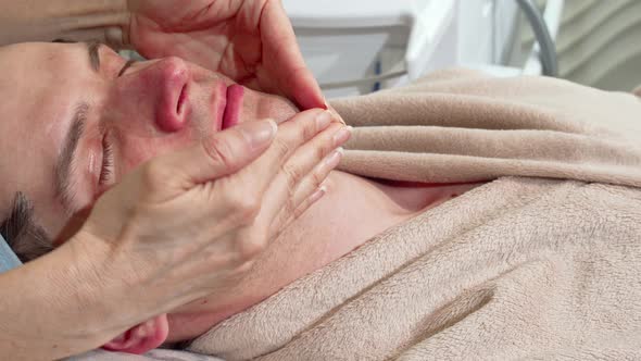 Sliding Shot of a Man Relaxing at Spa, Receiving Face and Head Massage alt