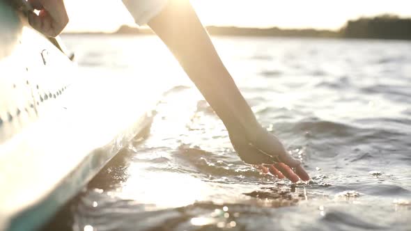 At Sunset, Close-up the Hand of a Girl Moving Through the Water