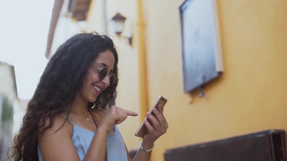 Smiling Young Woman Using Smartphone and Social Networking in Summer