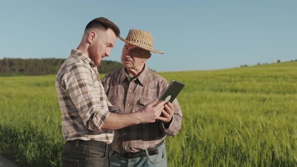 A Man is Showing an Old Farmer Information on a Tablet alt