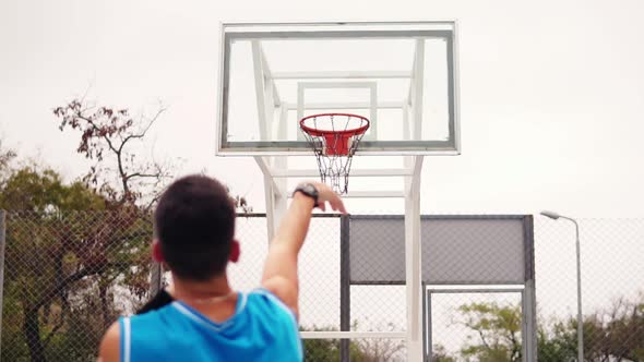 Back View of Unrecognizable Player Throwing Ball in a Basketball Hoop the Ball Hits the Ring and alt