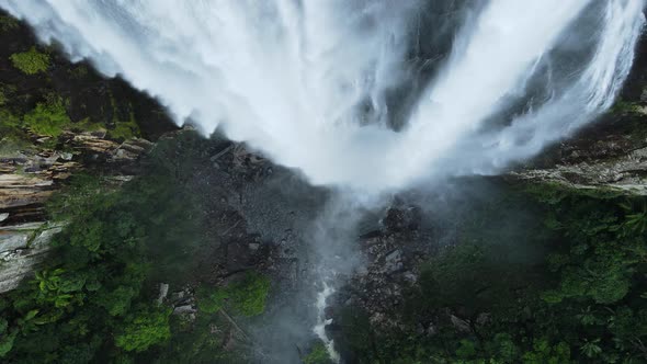 Unique view cascading down a majestic waterfall rising above a lush tropical rainforest. Moving dron alt