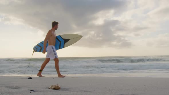Man walking with surfboard at beach 