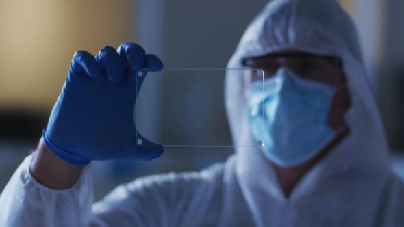 Caucasian Male Medical Worker Wearing Protective Clothing And Gloves Using Handheld Interface In