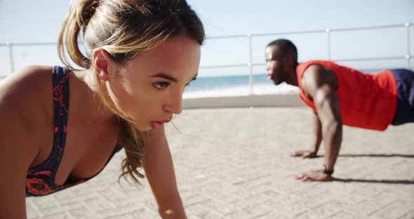 Couple doing push-up exercise on a promenade at beach 4k