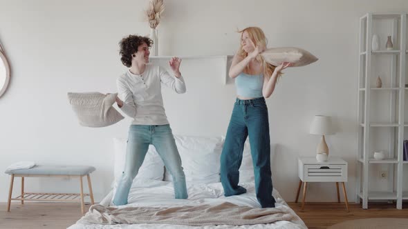 Happy Playful Couple Fun Pillow Fight on Bed Carefree Couple Funny Playing Leisure Game in Bedroom alt