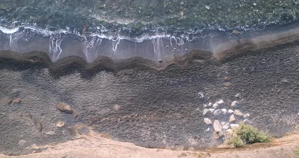 Drone Shot Looking Down at Waves Coming on the Black Sand Beach in Cap d'Agde FR