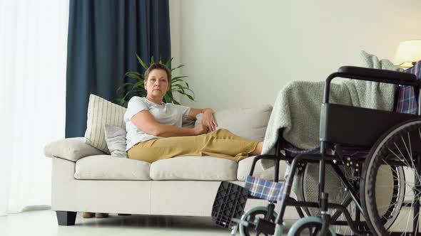 Portrait of Senior Woman with Wheelchair Looking at Camera in Living Room alt
