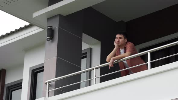 lonely man quarantine in balcony of his home with falling rain, coronavirus pandemic concept
