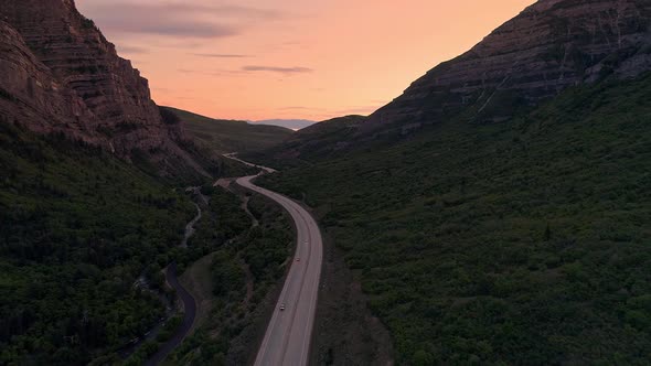 Flying through canyon with road winding through the landscape alt