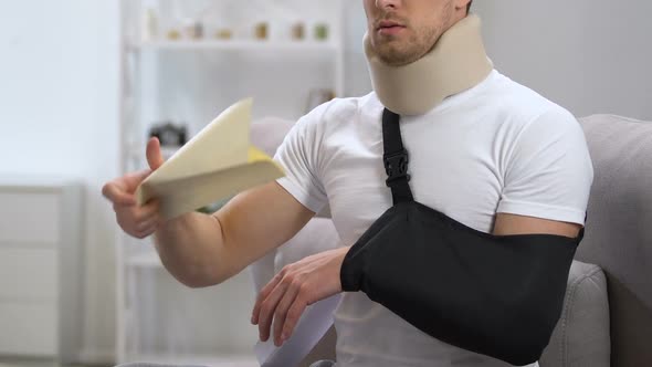 Male in Cervical Collar and Arm Sling Opening Envelope With Bill Using One Hand alt