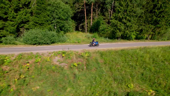 A Young Man Rides a Motorcycle Outside the City