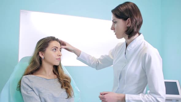 A Cosmetologist and a Patient in a Bright Office at a Consultation Discuss Treatment. Woman