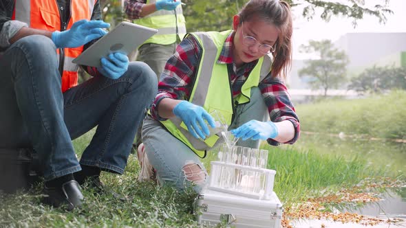 Biological engineer woman collecting samples of factory wastewater in a test tube