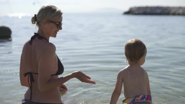 Mom and Baby Went Into the Water. Girl Hugging Mom From Fright. Morning Croatia.