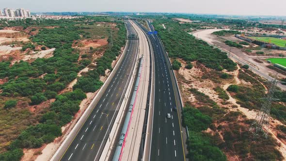 A train travels to the city near the highway. alt
