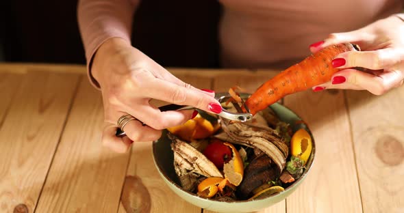 Women scraps peels carrots vegetable peeling, throws in compost bucket, organic composting alt
