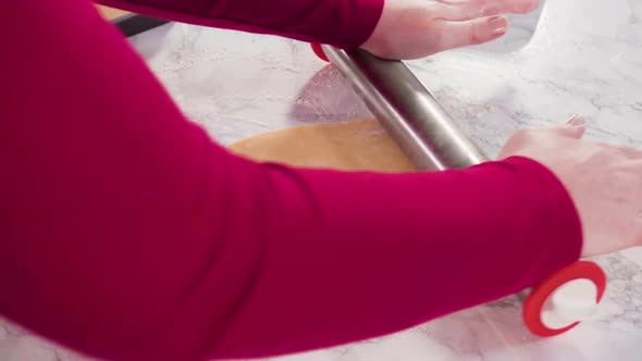 Rolling out sugar cookie dough to bake Christmas cookies. alt