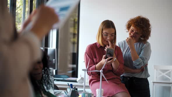 Young woman using smartphone during meeting with wind wheels alt
