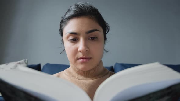 Close Up View From Below A Young Indian Woman Reads A Book And Turns The Page alt