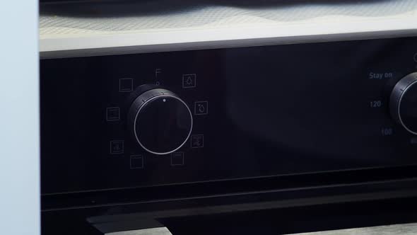 Women's Hand Turns on Oven alt