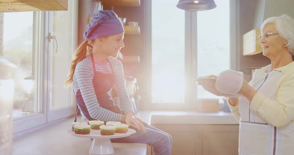 Grandma letting little girl to smell freshly baked muffins  alt