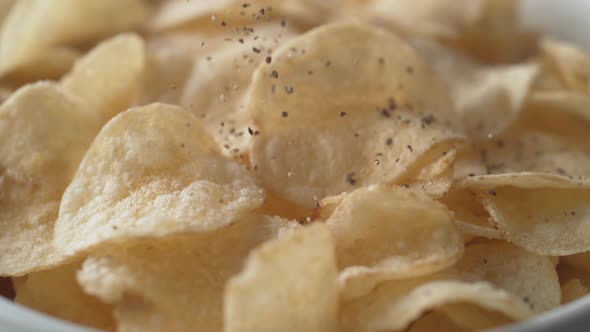 Adding black pepper on potato chips. Slow Motion. alt