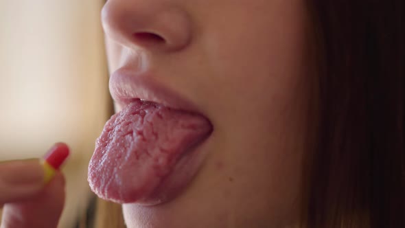 Close-up View of Female Hand Putting Pill on Her Tongue. Troubled Teens. Drug Addiction alt