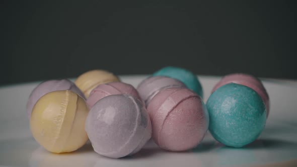Bath Bombs in Different Colors Spin Against a Black Background alt