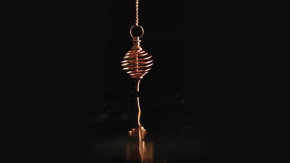 Golden Energy Pendulum in The Form of a Spiral Swings Over Black