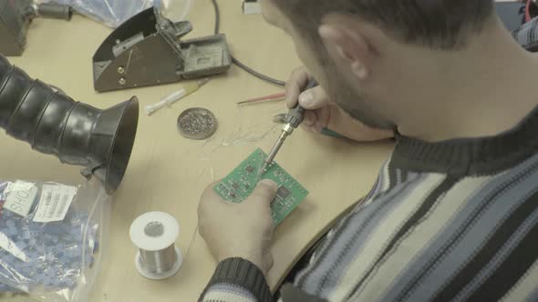 A Worker Is Working on the Production of an Electronic Board. Close-up. alt