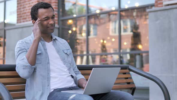 Sitting Outdoor African Man with Headache Using Laptop alt