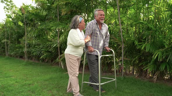 Elderly couple, an elderly man learning to walk on a walker in the garden